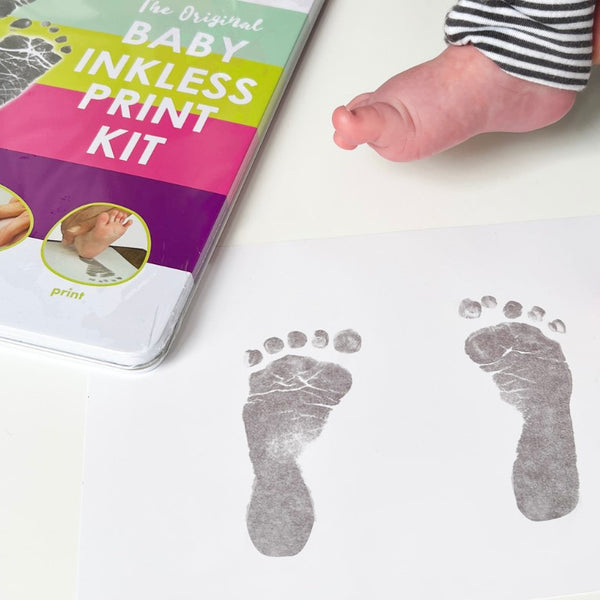 The image shows a Baby Inkless Print Kit packaging with a baby's footprints below it, indicating the kit's use for capturing such prints.